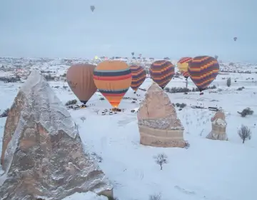 Mongolfiere in Cappadocia sopra valli con camini delle fate