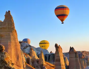 Golden morning light on rising Cappadocia balloons