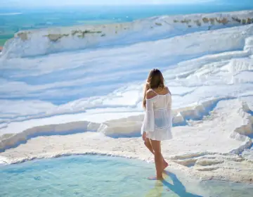 Woman walking on Pamukkale white terraces panorama