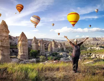 Man walking in fairy chimney landscape with balloons