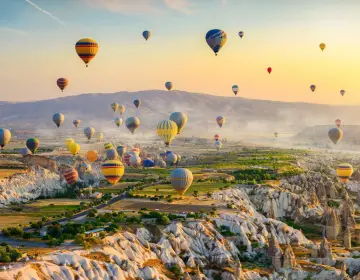 Mongolfiere in Cappadocia sopra valli con camini delle fate