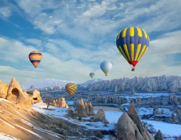 Snowy rock peaks with Cappadocia balloons
