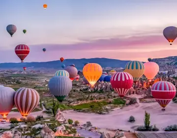 Mongolfiere in Cappadocia all alba sopra valli con camini delle fate