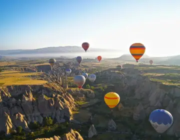 Mongolfiere in Cappadocia all alba sopra valli con camini delle fate