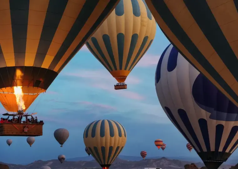Sunlit balloon flight over valley rocks in Cappadocia